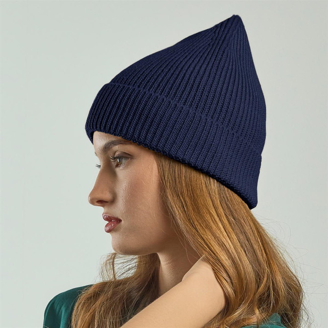 A navy beanie displayed on a model, featuring a ribbed texture and a pointed top, with a logo on the front.