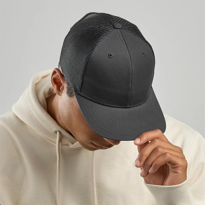 A grey trucker cap with a solid front and mesh back, worn by a person in a cream hoodie.