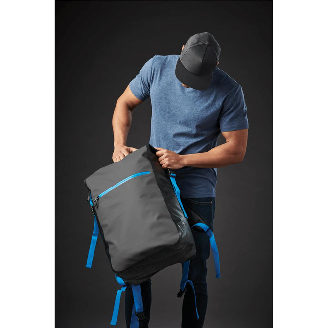 A person wearing a cap is checking a grey backpack with blue accents and a logo.