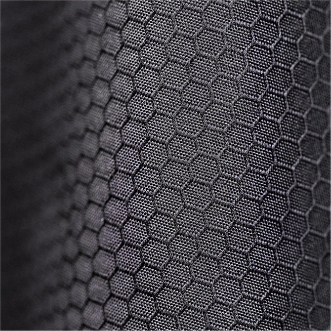 A close-up of a textured black fabric featuring a hexagonal pattern. The fabric appears durable and supportive.