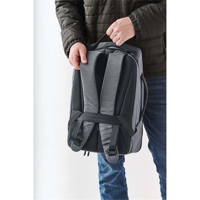 A grey Toluca backpack being held by a person, featuring padded straps and a sleek design.
