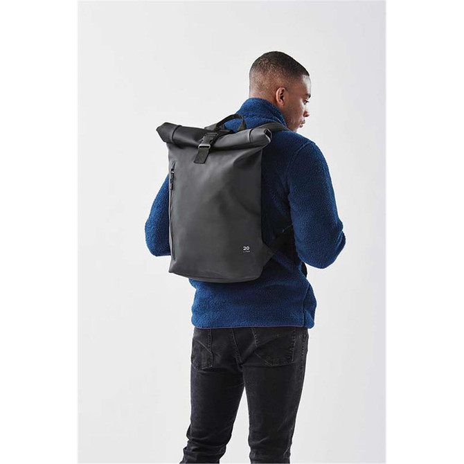 A black Sargasso backpack with a roll-top design, worn by a person in a blue fleece jacket. The bag features a logo.