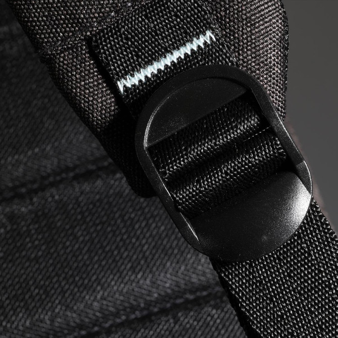 A detailed close-up of a black backpack strap featuring a plastic buckle, showcasing its durable materials and design.