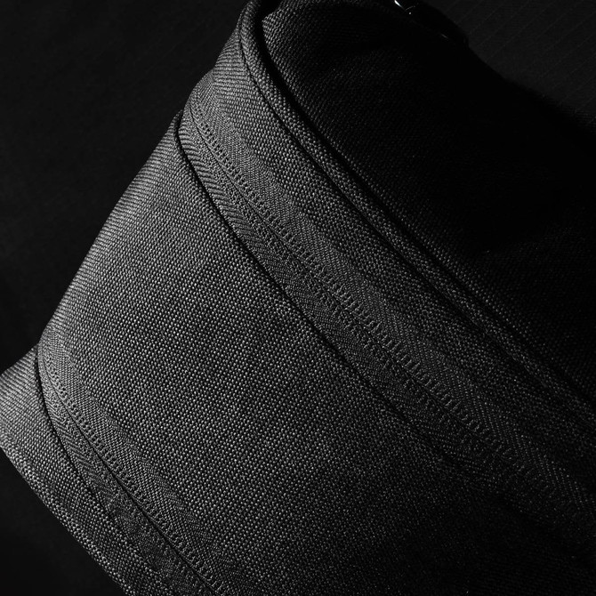 A black toiletry bag with a textured fabric surface and zippers, featuring a small logo.