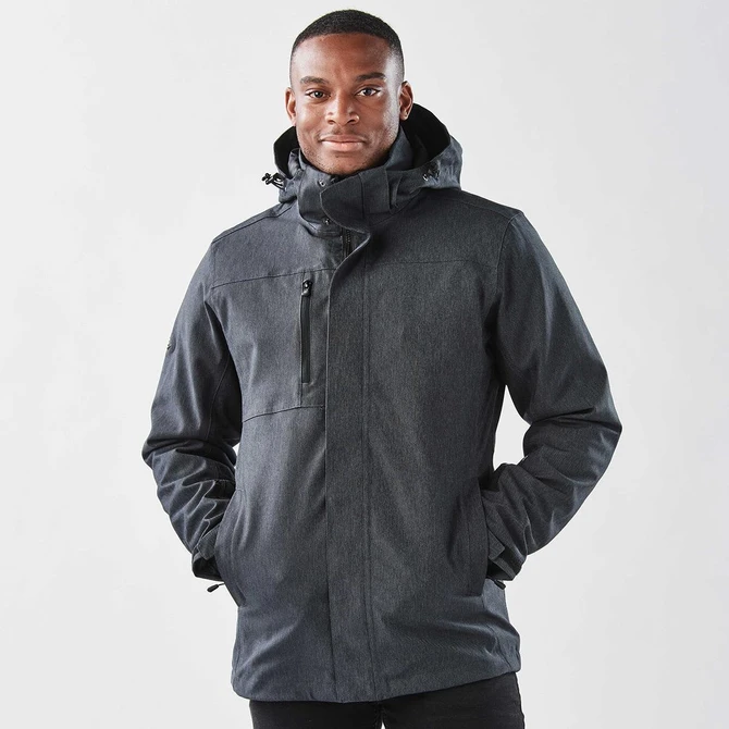 A man wearing a black jacket with a hood, featuring a zipper and pockets, against a plain background.