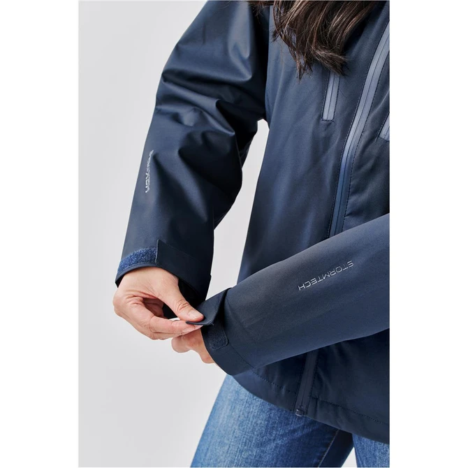 A navy blue women's lightweight shell jacket with a logo, featuring adjustable cuffs and a fitted design.