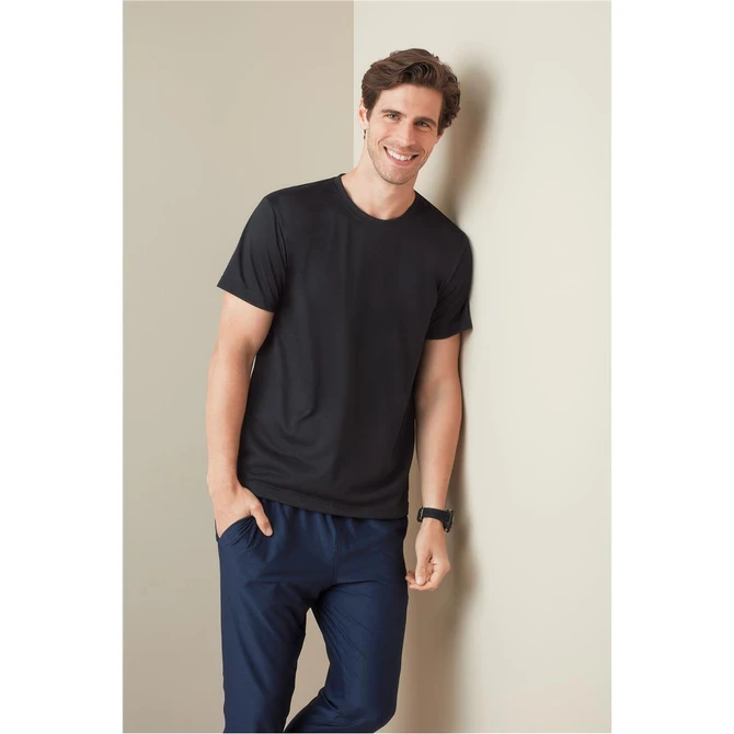 A black men's active cotton touch t-shirt, worn by a smiling man, paired with navy pants, against a light background.