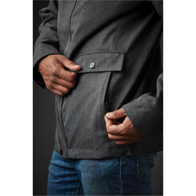 A close-up of a person wearing a dark grey Men's Montauk System Jacket, featuring a front pocket and a button detail.