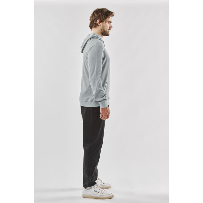 A side view of a man wearing a grey pullover hoody with a hood, paired with black pants and white shoes.