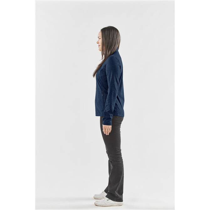 A woman stands in profile wearing a navy blue performance jacket and black pants, showcasing a casual look.