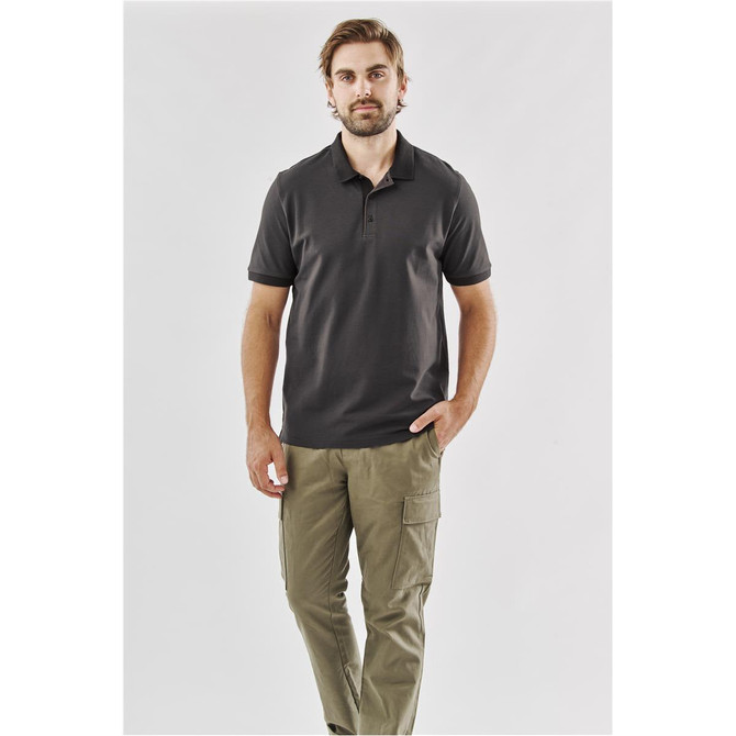 A man wearing a dark grey polo shirt paired with khaki cargo pants. The shirt features a logo.
