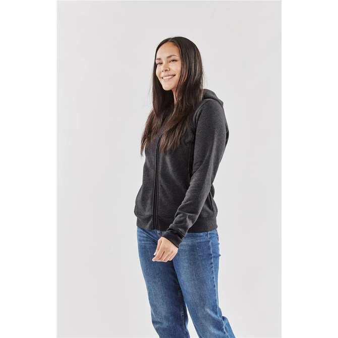 A woman wearing a black fleece full zip hoodie, styled with a neutral background and casual blue jeans.