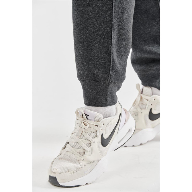 A pair of dark grey fleece joggers with elastic cuffs, paired with light-coloured sneakers featuring a logo.