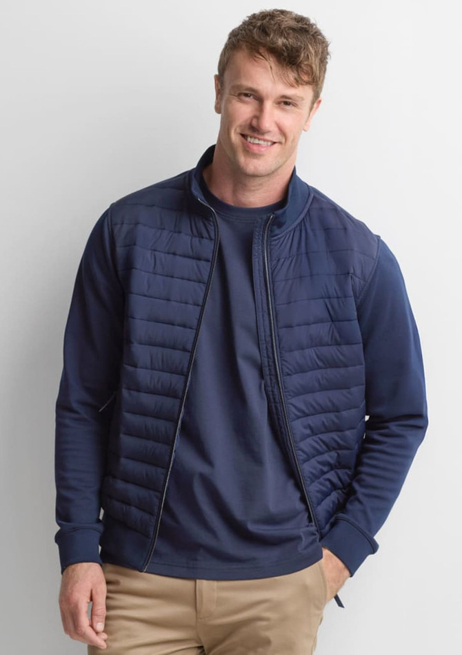 A men's tailor jacket in navy blue, featuring a quilted design and zip-up front, displayed on a smiling model.