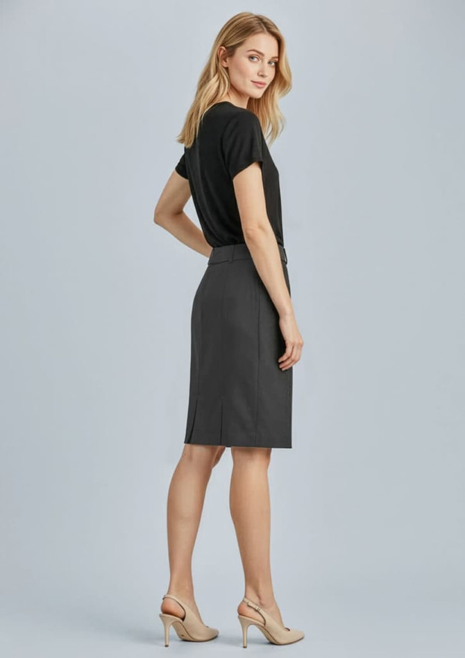 A woman stands wearing a grey pleated skirt and a black top, showcasing a sleek, professional look.