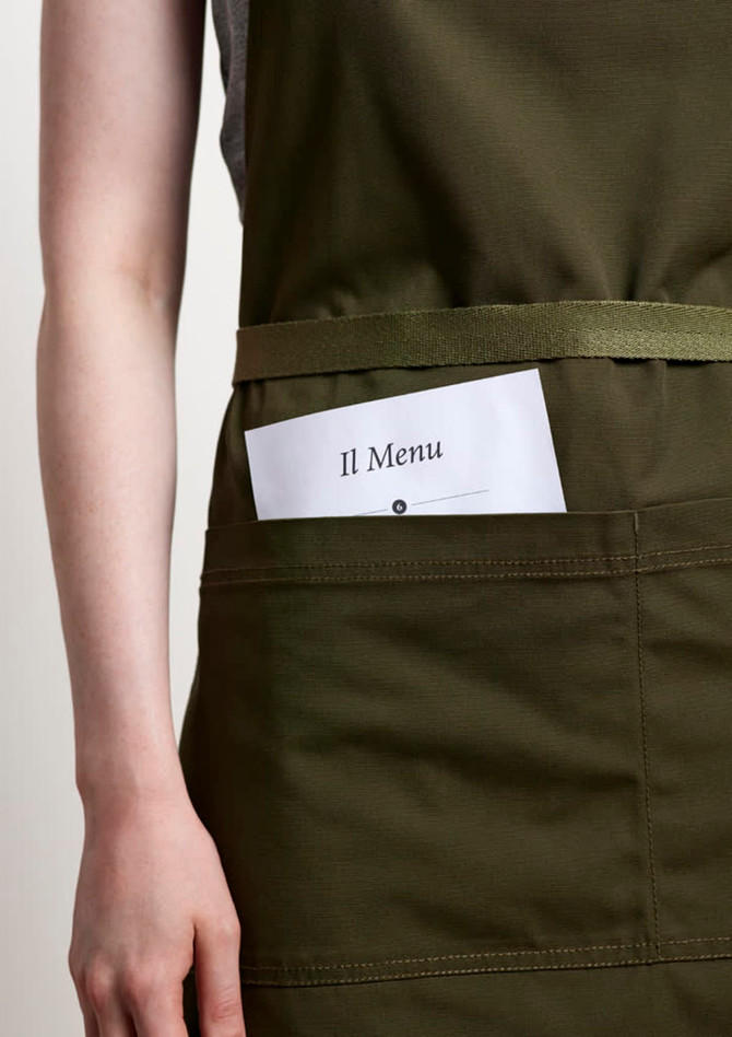 A green apron featuring a front pocket holding a menu card, with a simple logo.