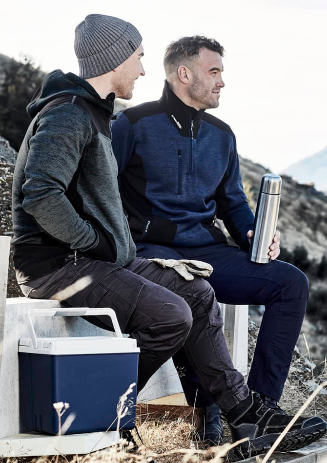 A grey and navy unisex hoodie is worn by two men sitting outdoors, one holding a drink bottle and a cooler nearby.