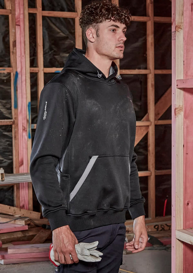 A unisex water-resistant hoodie in black, featuring a logo and pockets, worn by a model in a construction setting.