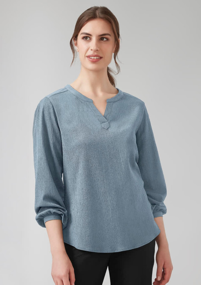 A blue women's long sleeve blouse with a V-neck and ruché detailing. The fabric has a textured look.