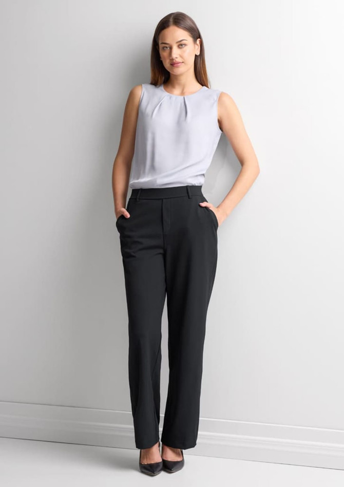 A woman wearing black soft stretch pants paired with a light grey top, standing against a plain background.