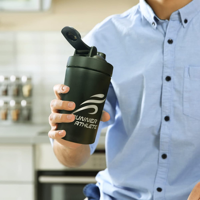 A drink bottle in matte black with a flip-top lid, featuring a logo on the side, held by a person in a light blue shirt.