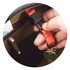 A hand holding a red strap clip inside a black and brown bag, with a keychain and various items visible.