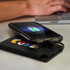 A black power bank with a logo, connected to a phone displaying a charging symbol.