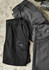 A pair of men's work shorts in black and grey, featuring pockets and a logo. The fabric has a sturdy texture.