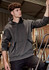 A unisex dark grey water-resistant hoodie with a front pocket and a hood, displayed in a work environment.