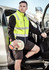 A unisex hi-vis softshell vest in fluorescent yellow with reflective stripes, worn by a man exiting a vehicle.