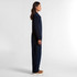 A navy blue canvas coverall with a fitted style, featured from the side. The model stands against a plain background.