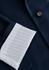 A navy jacket featuring a white striped cuff and a button detail, with a branding logo present.