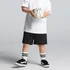 Black track shorts worn with a white T-shirt and black sneakers, holding a basketball. The outfit includes striped socks.