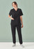 A woman wearing a black V-neck scrub top and matching pants, with a pocket, set against a green background.