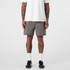 A pair of grey dress shorts featuring a simple design and a logo, modelled by a person with tattoos.