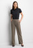 A woman wearing a black short sleeve polo shirt paired with beige trousers, standing confidently with her hands in her pockets.