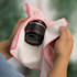 A hands holding a pink and white patterned cloth with a black camera lens partially wrapped inside.