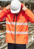 A vibrant orange packable rain jacket with reflective stripes, worn by a person in a hard hat.