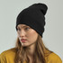 A black ribbed beanie is worn by a model with long hair, styled casually against a neutral background.