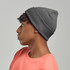 A grey beanie made from recycled polyester, worn by a model with short, curly hair.