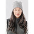 A grey knit beanie displayed on a model with long hair, featuring a simple design and a logo.