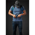 A person adjusts the straps on a blue Kemano Backpack while wearing a grey T-shirt and a cap. The backpack features black accents.