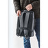 A grey Toluca backpack being held by a person, featuring padded straps and a sleek design.