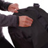 A person is adjusting the top flap of a black Nomad Duffle Bag, which features a logo. The bag is made of durable material.