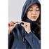 A woman adjusts the fastening on a navy lightweight rain jacket with a hood, featuring a logo on the sleeve.