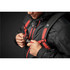 A person securing the straps of a black backpack with red accents, featuring a logo and a detailed harness system.