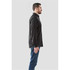 A men's long sleeve button-up shirt in black, displayed on a model from the side view. The shirt features a collar and has a logo.