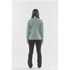 A back view of a women's performance jacket in a soft green colour, paired with black pants. The jacket features a logo.