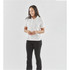 A woman stands wearing a white polo shirt and black pants. The shirt has a logo on it.
