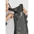 A woman examines the interior of a women's rain jacket in dark green, featuring mesh detailing and ventilation.